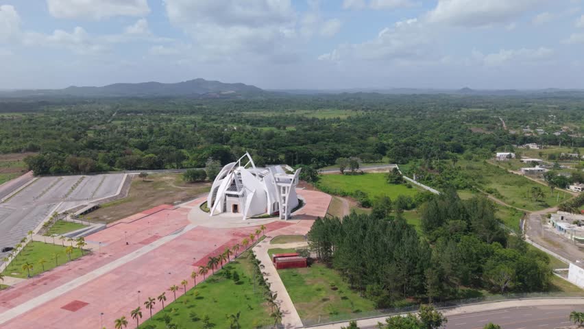 Wide-angle aerial drone shot capturing the full scale of the National Sanctuary in Bayaguana, showcasing its modern white structure within a lush green rural landscape