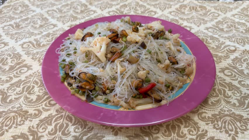 Vibrant vermicelli mussels cauliflower peas plate, colorful porcelain plate showcasing transparent noodles topped with mussels