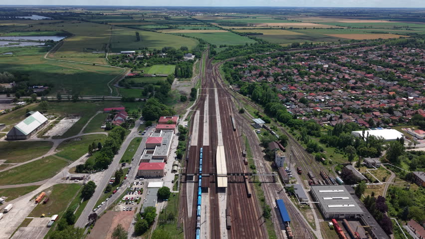 An aerial perspective displays the extensive railway station infrastructure and surrounding rural town layout in Kiskunfelegyhaza, Hungary, on a clear day.