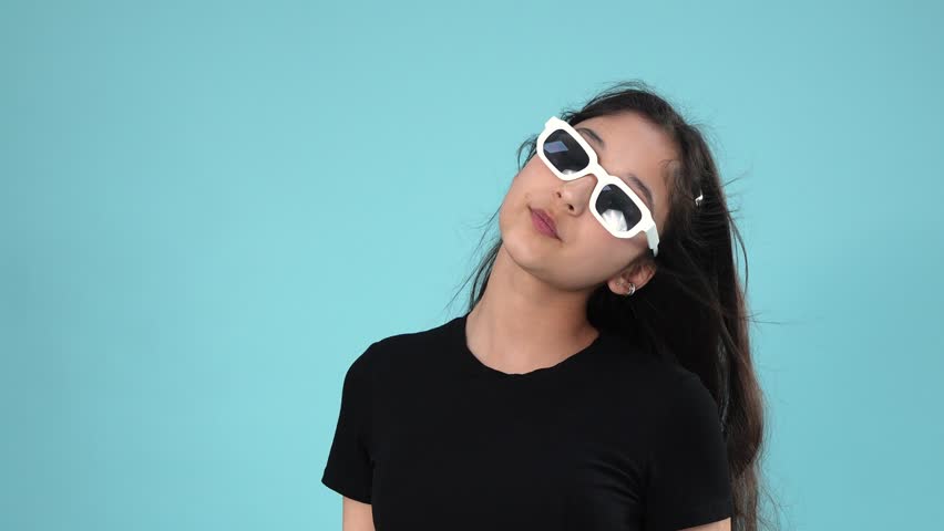 Stylish teenage girl posing in white sunglasses on blue background