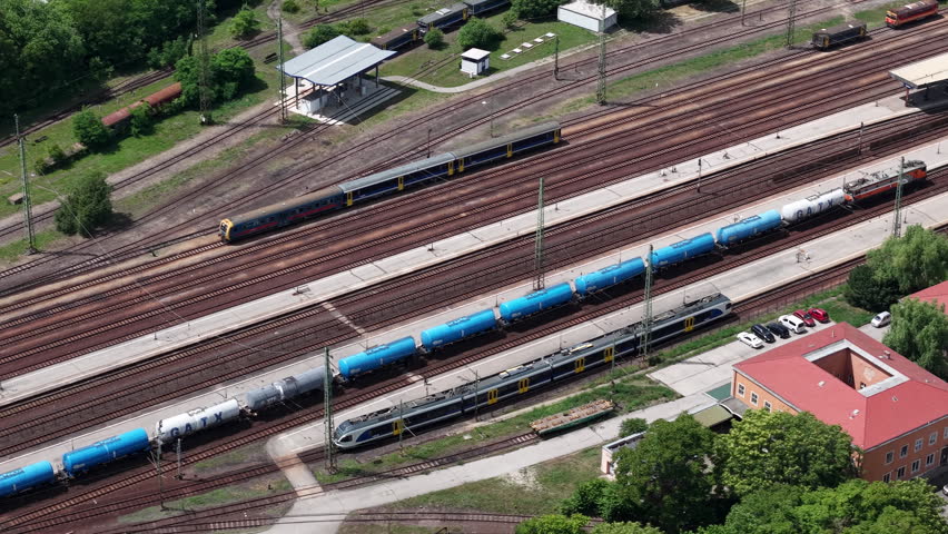 An aerial overhead view shows passenger and freight trains at a busy railway station in Hungary for logistics transport.