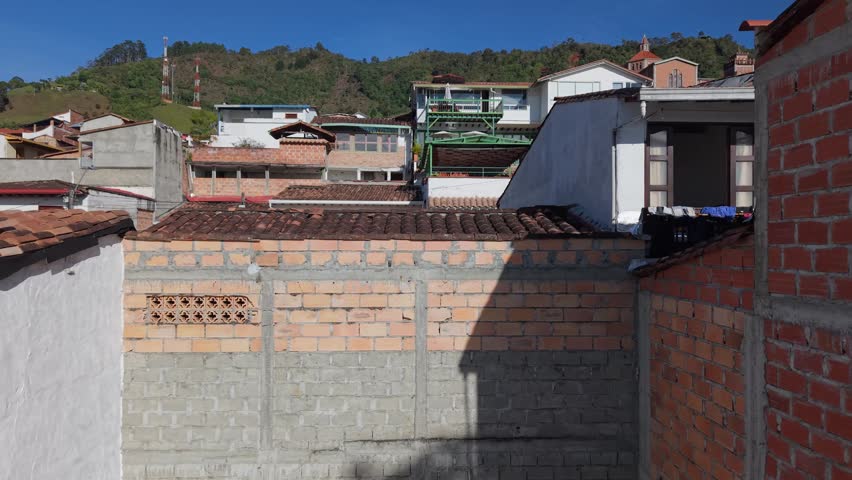 Aerial view over Jerico rooftops with large church and lush green hills in background