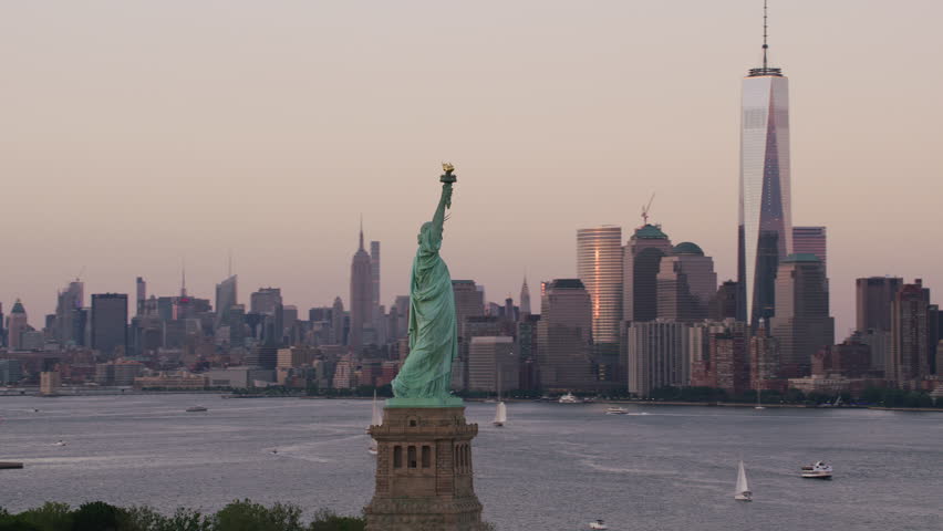 Aerial view of statue of liberty in New York City with Manhattan skyline in distance.  Shot from Helicopter with RED camera and stabilized gimbal.  