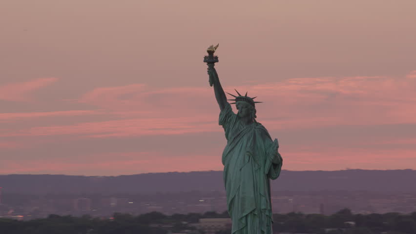 Aerial view of statue of liberty in New York City with Manhattan skyline in distance.  Shot from Helicopter with RED camera and stabilized gimbal.  