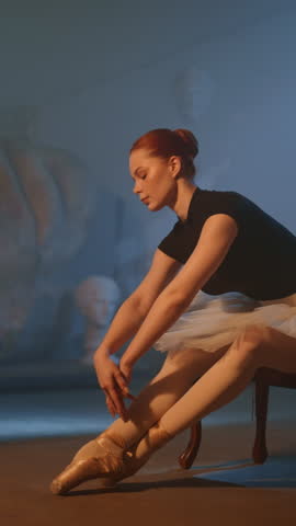 Female ballet dancer stretch body before rehearsing, amazing slow motion shot. Training and preparing to performing on stage, talented ballerina in white tutu and point shoes, classical arts and music