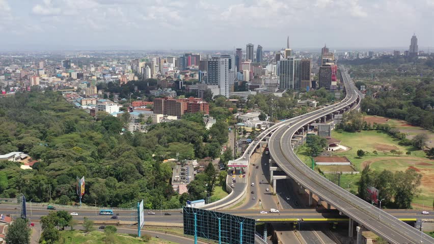Aerial view of the Nairobi Expressway winding through the urban landscape with modern skyscrapers and lush green trees, Nairobi, Nairobi County, Kenya.