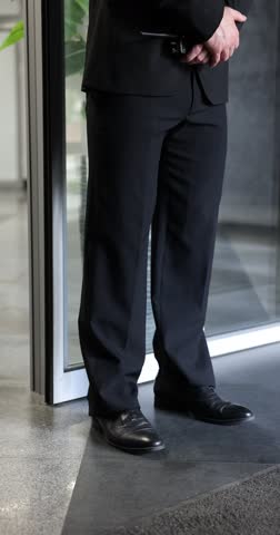 Bodyguard with walkie talkie and earpiece indoors, camera moving up