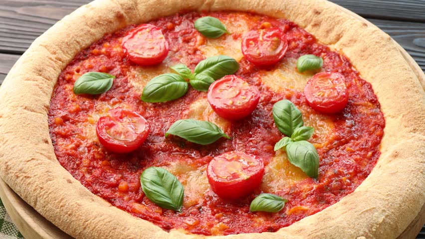 Yummy Margherita pizza on dark wooden table, spinning. Closeup view