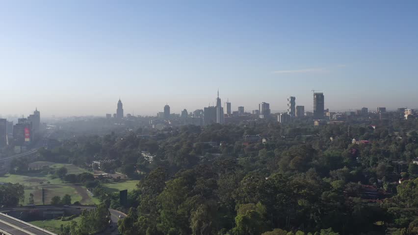 Aerial view of the Westlands business district skyline with modern skyscrapers rising above lush green trees under a clear sky in Nairobi, Nairobi County, Kenya.