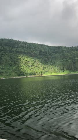 Scenic video of Telaga Menjer lake in Wonosobo, Central Java, Indonesia, with calm water, misty green mountains, cloudy sky, and peaceful natural scenery.