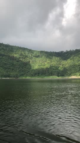 Scenic video of Telaga Menjer lake in Wonosobo, Central Java, Indonesia, with calm water, misty green mountains, cloudy sky, and peaceful natural scenery.
