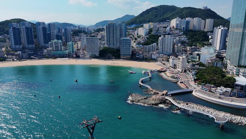 Aerial view from a cable car cabin descending over the turquoise sea towards songdo beach and the city skyline of busan, south korea