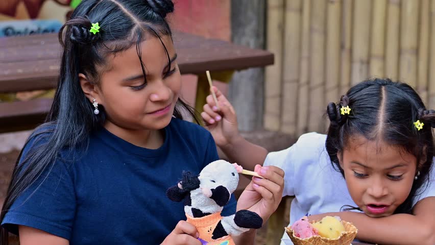 Latina girls eating ice cream and playing with their stuffed animal