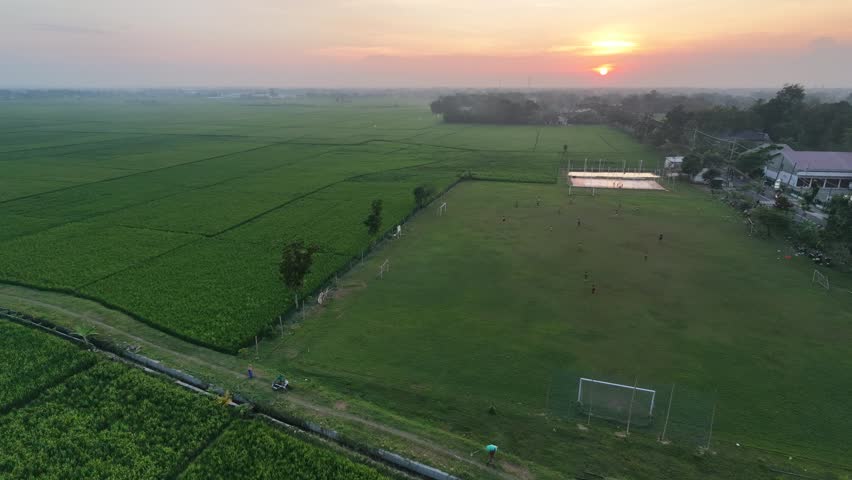 Breathtaking golden hour sunset over lush green rice fields in a peaceful countryside.