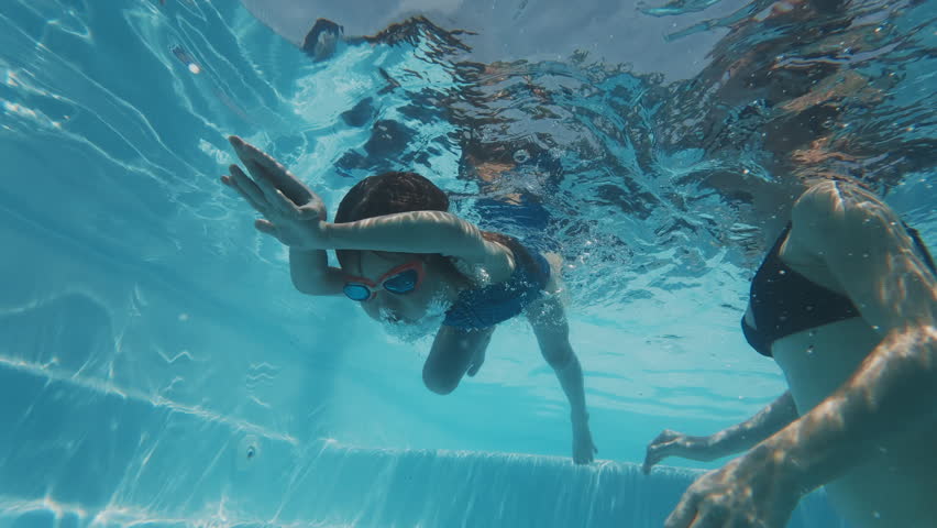 Girl swims underwater in the pool. Pre teen girl feels herself comfortable and relaxed underwater. Little girl dives and swims in the pool