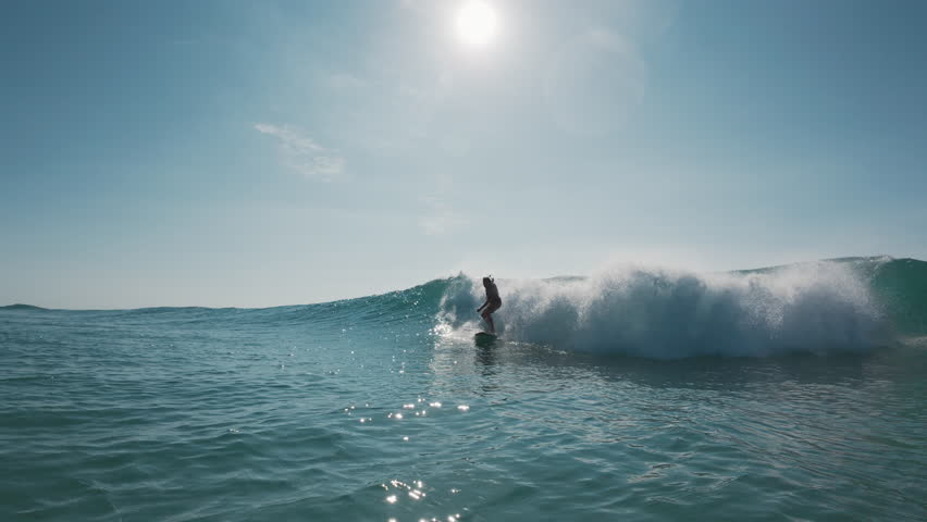 Stylish surfer. Young man in bright colorful shirt surfs the wave. Speed warp effect applied with frozen movement of the rider