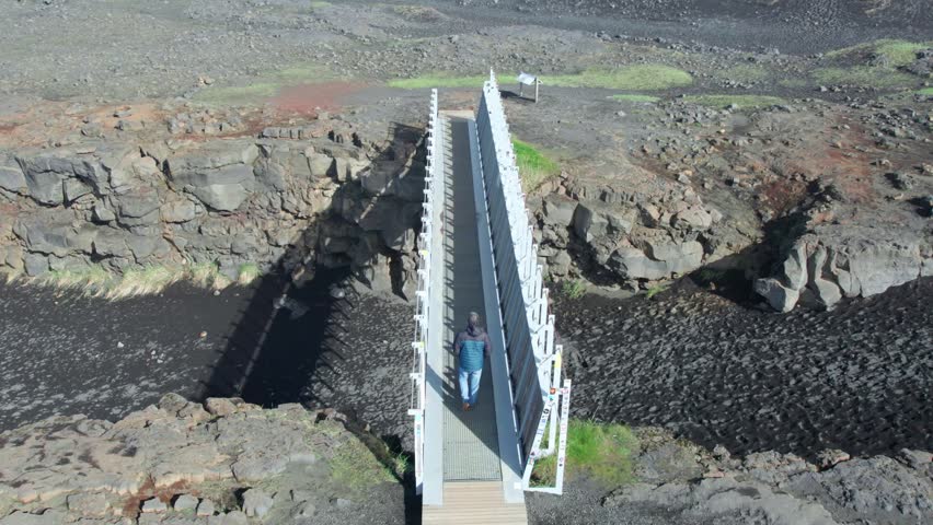 Visitor strolling along the Mid Atlantic Ridge footbridge that links the Eurasian and North American tectonic plates in the Reykjanes Peninsula, Iceland.