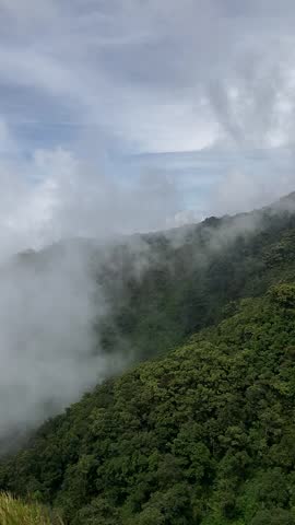 Portrait view on top of Mount Ungaran, Central Java, Indonesia. Clouds and fog are visible.