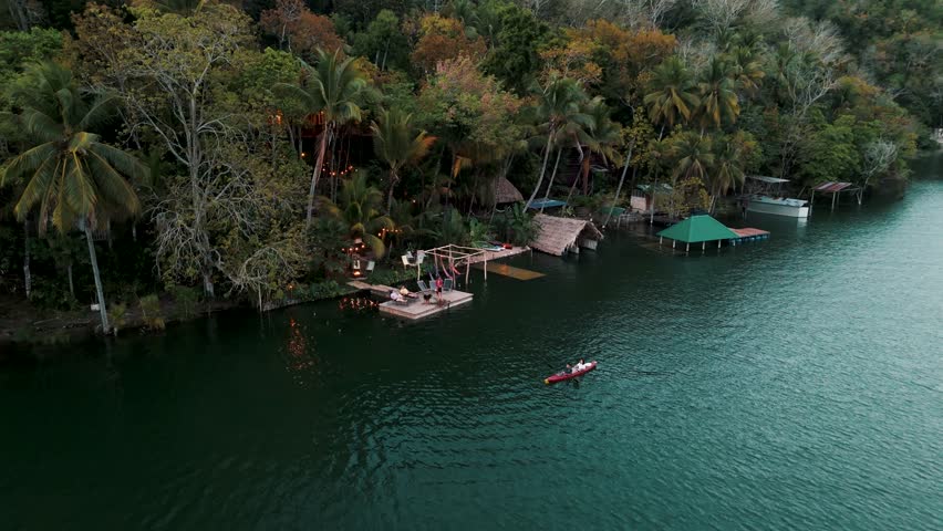 High angle drone footage of a cozy jungle eco lodge on a lake in Peten, Guatemala.