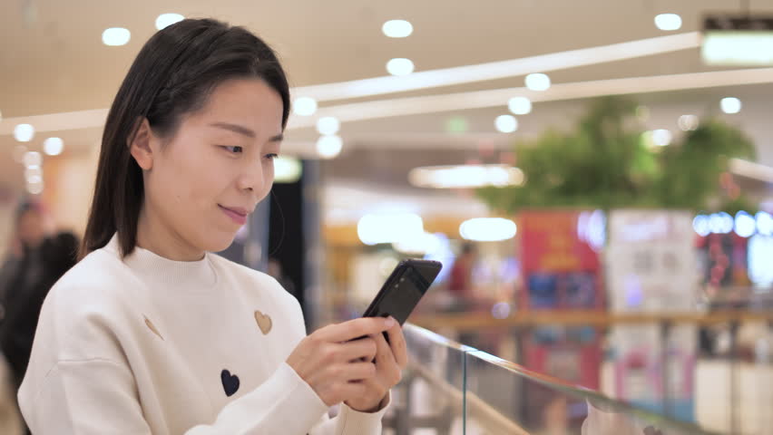 Asian women from East Asia, including China, use their mobile phones to communicate in a shopping mall.