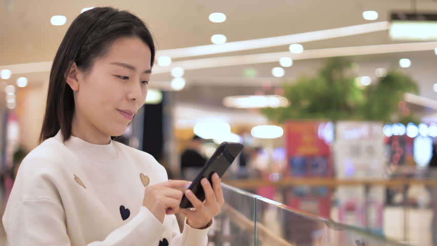 Asian women from East Asia, including China, use their mobile phones to communicate in a shopping mall.