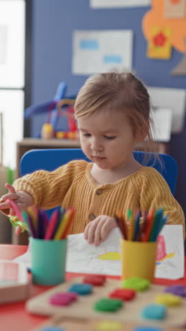 Girl cuts paper with scissors, hand holding scissors at a table in a studio; concentration creativity play.