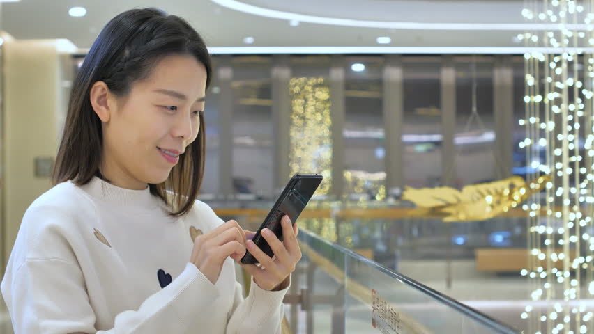 Asian women from East Asia, including China, use their mobile phones to communicate in a shopping mall.