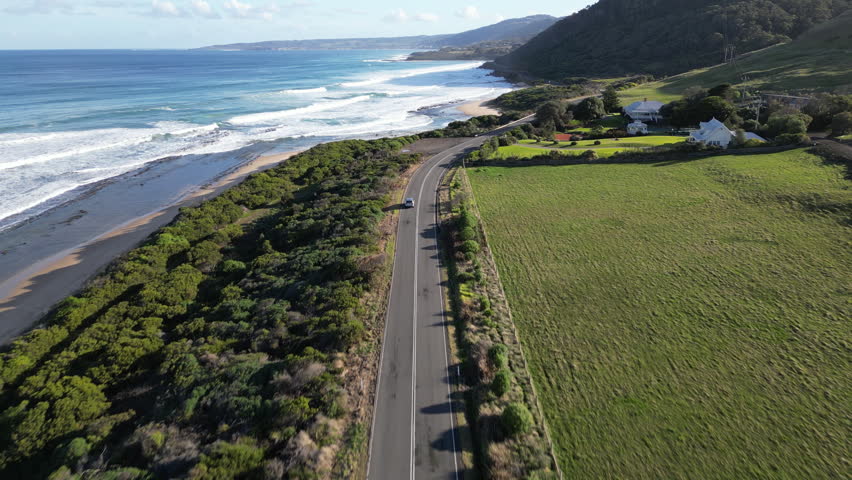 Scenic aerial flight above Great Ocean Road Australia with rugged cliffs rolling mountains and road tracing the Southern Ocean shore