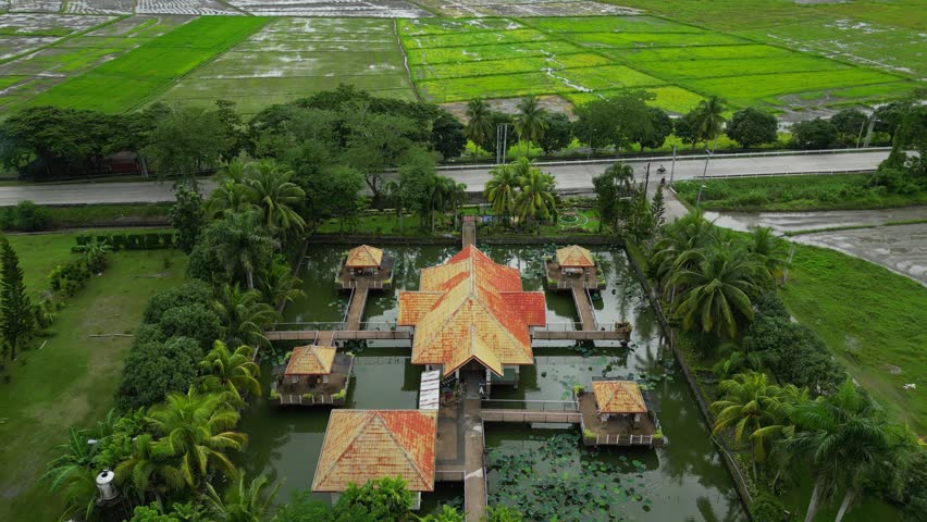 A pull-out aerial of Palaisdaan Hotel reveals water villas with orange roofs framed by tropical trees Bagabag, Nueva Vizcaya, Philippines