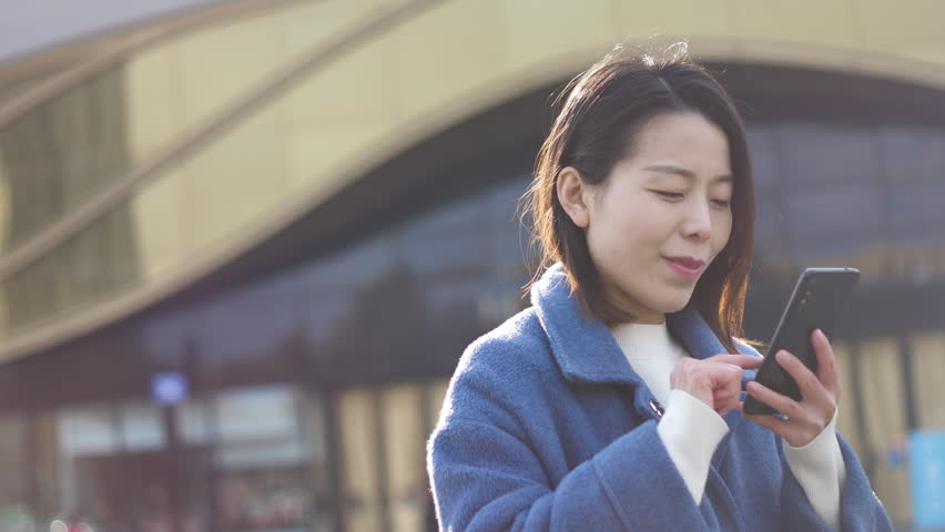 Asian women from East Asia, including China, use their mobile phones to communicate in a shopping mall.