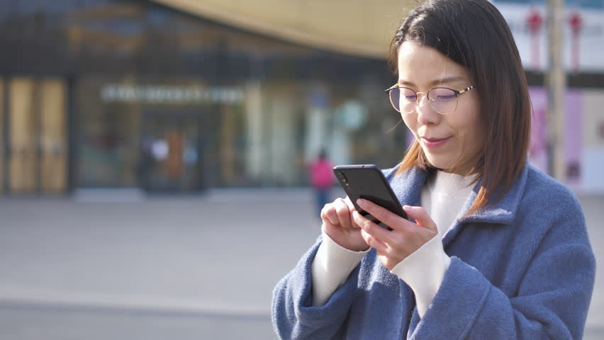 Asian women from East Asia, including China, use their mobile phones to communicate in a shopping mall.