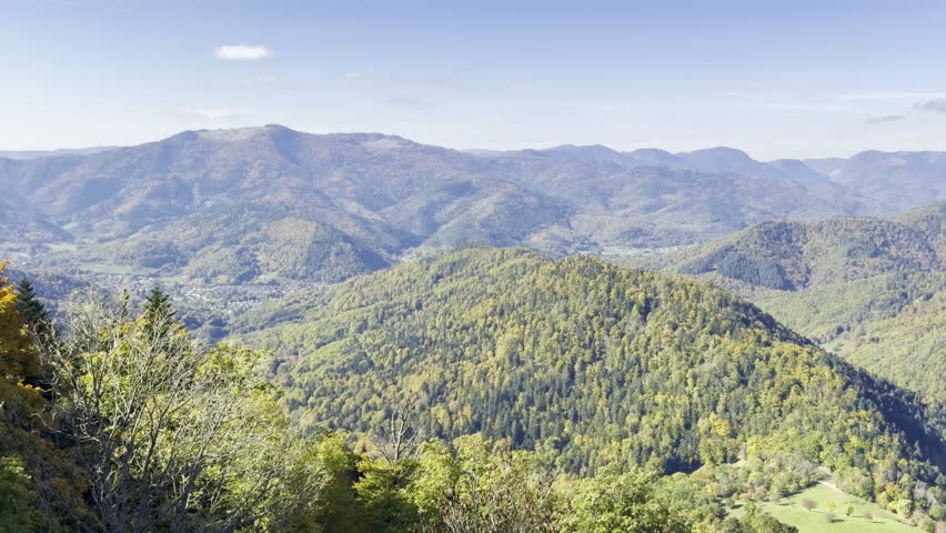 Panning video over the forested Vosges mountains in autumn, looking across a valley and distant ridges from a viewpoint near Hartmannswillerkopf in southern Alsace, France