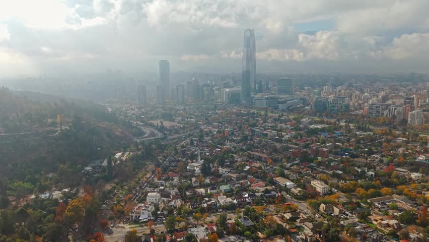 Aerial view establishing of Santiago, Chile, in the fall, with clouds in the background covering the Andes Mountains, the downtown area, and the financial district
