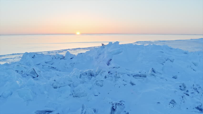 Polar bear mother with her cub exploring a frozen arctic landscape at sunrise over the ocean