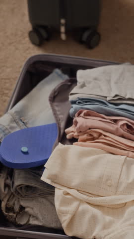 Vertical video of young adult Caucasian couple using laptop and smartphone to book vacation online near packed suitcase. Perfect for travel agency promos and online booking services