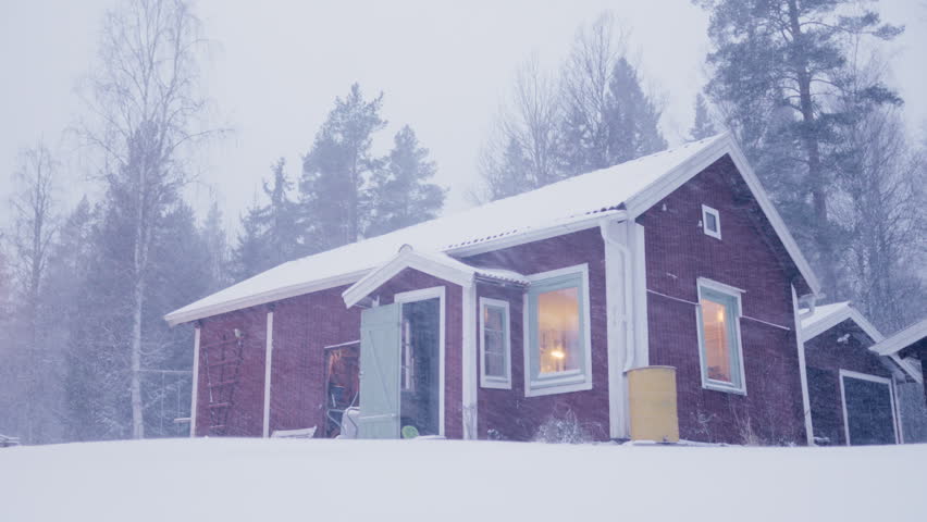 Man exits traditional red Swedish house into cold blizzard conditions in winter