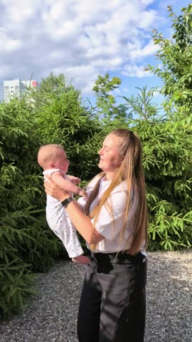 Mother Lifting Happy Baby Outdoors In Summer