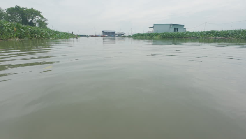 Rural Vietnam lifestyle, person using a red plastic bowl to scoop water at An Hiep floating village, Dong Thap