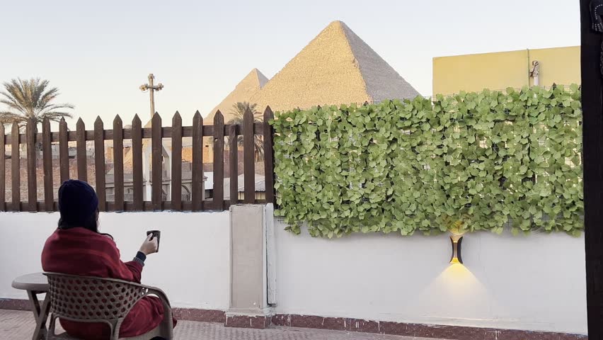 Woman Enjoying Coffee with the Pyramids of Giza in Egypt
