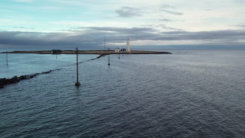 Dramatic aerial view of the iconic Grotta lighthouse. This tranquil seascape captures the peninsula of Reykjavik under an overcast sky