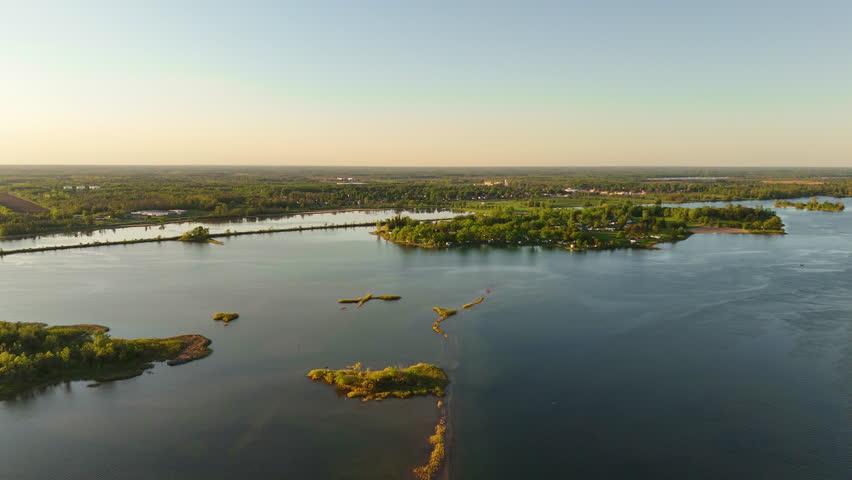 Aerial view of a submerged historic roadway near St. Lawrence Parks in Ontario, Canada, with Farran Park Island in the background and a long shoreline cycling path bordered by water.