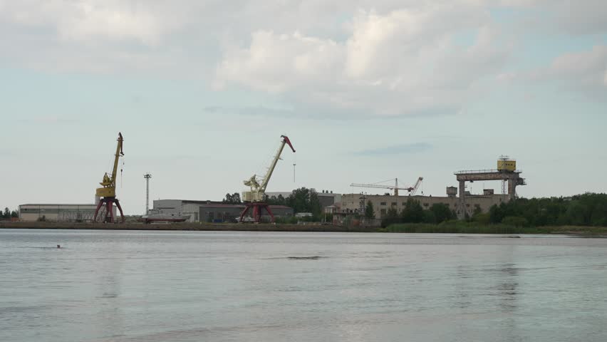 Abandoned shipyard with old rusty cranes near the sea.