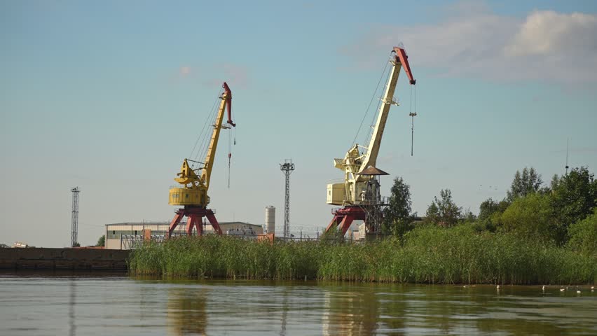 Abandoned shipyard with old rusty cranes near the sea.