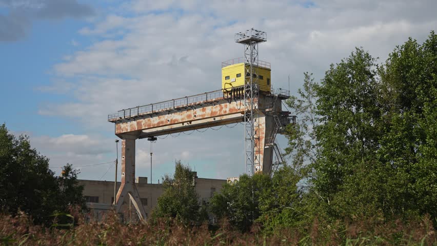 Abandoned shipyard with old rusty cranes near the sea.