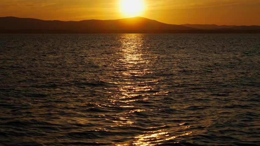 A beautiful golden sunset with a landscape view of the lake and the mountain range on the horizon. Extraordinary natural beauty.	