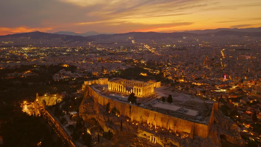 Majestic aerial view of the illuminated acropolis of athens, with the historic parthenon temple glowing against the backdrop of the sprawling city skyline during a beautiful twilight sunset
