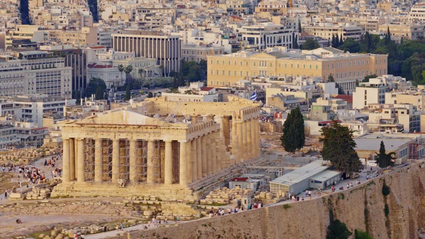 Aerial view of the ancient parthenon on the acropolis, a historic landmark surrounded by the sprawling cityscape of athens, greece, beautifully illuminated by the warm light of the setting sun