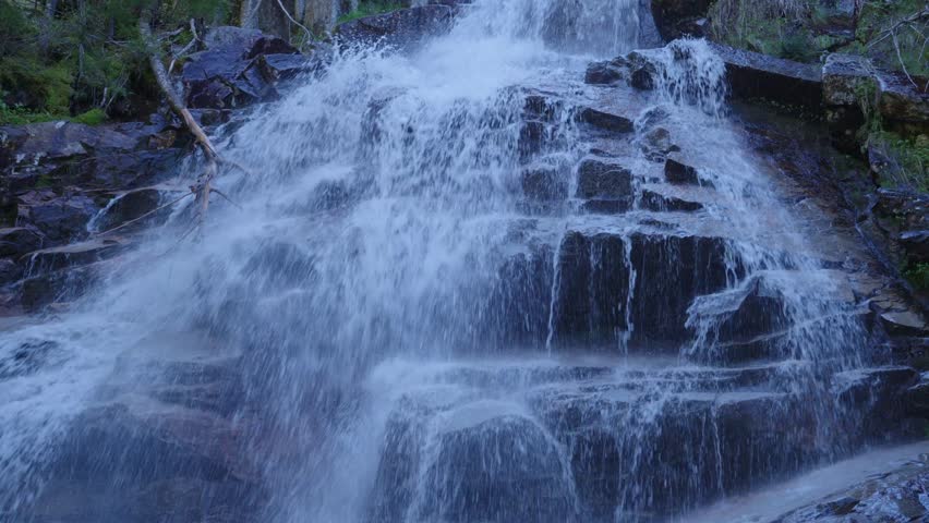 Fast flowing water cascading over dark wet rocks at Cloudland Falls in Lincoln, United States. Close-up