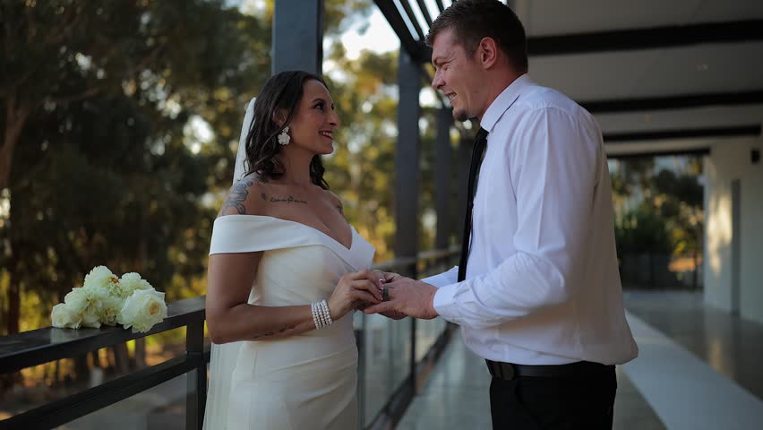 On wedding day, bride and groom on venue patio share sweet kiss