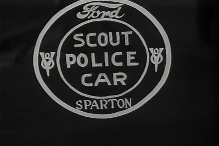 1930s - Police cars are parked in formation for a policeman